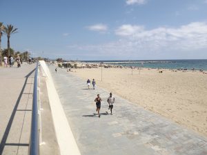 люди на пробежке на пляже в Барселоне