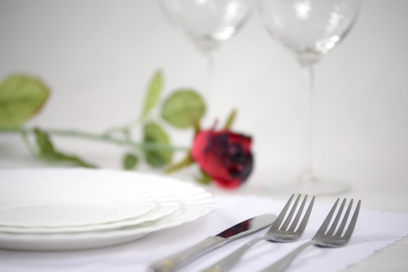 тарелка, вилки и роза на столе