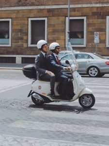 два человека в шлемах едут на скутере