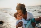 женщина обнимает ребенка на фоне моря
