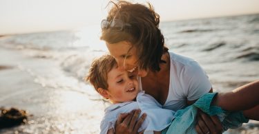 женщина обнимает ребенка на фоне моря