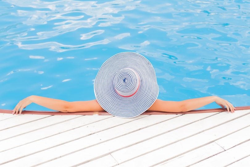 Женщина в шляпе отдыхает в бассейне