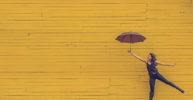 женщина с зонтиком на жёлтом фоне