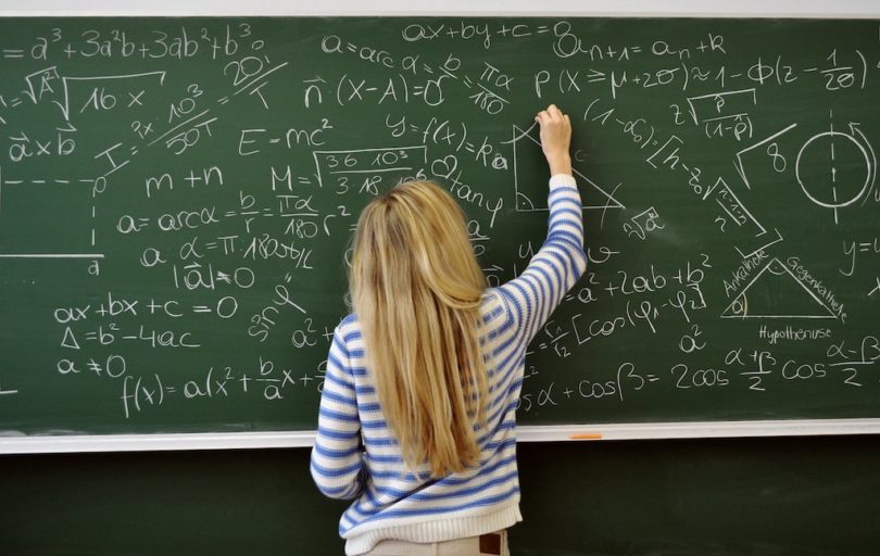 девушка решает математические задачи на доске