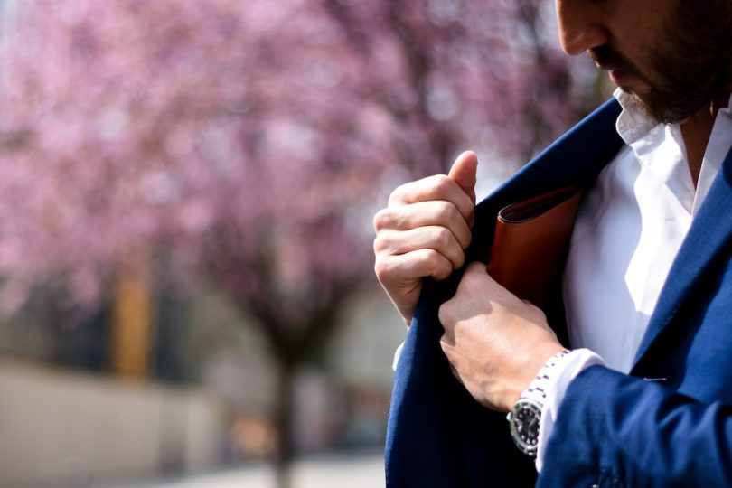мужчина в синем костюме кладет кошелек во внутренний карман
