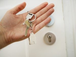 ключи в руке напротив белой двери
