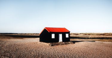 черный дом с красной крышей в пустыне